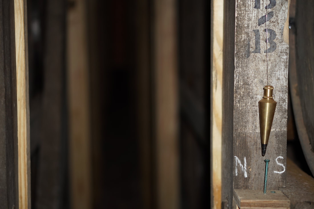A plumb bob hangs in a bourbon warehouse